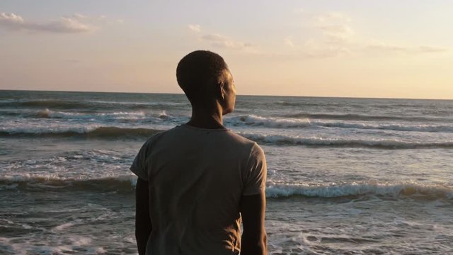 Missing Africa.sad Lonely young african man observing the sunset on the sea