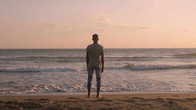 Joy,freedom, carefree. Young black african man opening arms on beach at sunset
