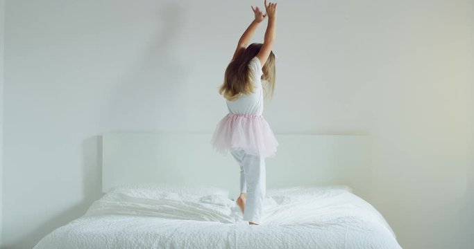 A little girl is dancing and plaA little girl is dancing and playing on her parents bed with a tutu. aying on her parents bed with a tutu. Concept: Freedom, happiness, family. Shot on Red 8K