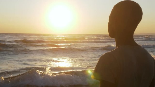 Lonely young african man on the bech contemplating the sunset. Missing Africa