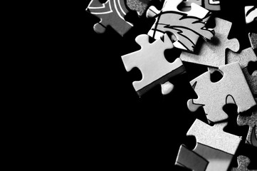 Pieces of children's puzzles scattered on a dark background close up. Black and white