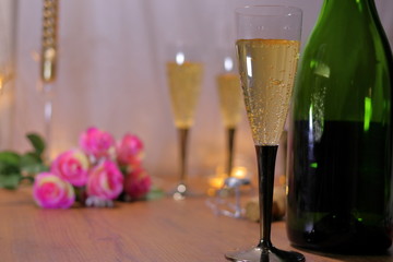 テーブルの上にシャンパンとシャンパンボトルと薔薇の花