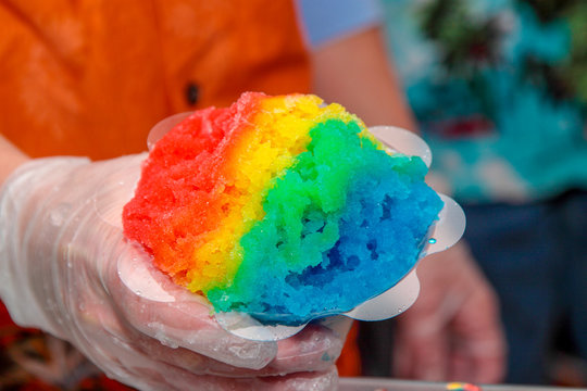 Hand Holding Cone Of Rainbow Colored Ball Of Shaved Ice