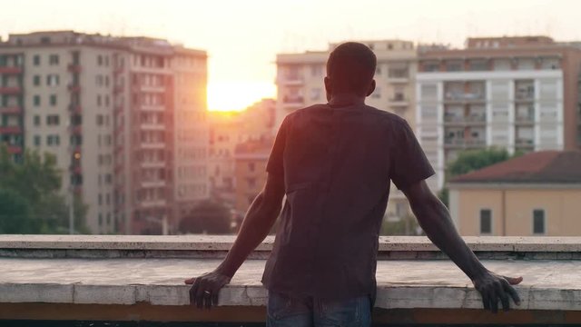 Young african man on the roof contemplating the city sunset