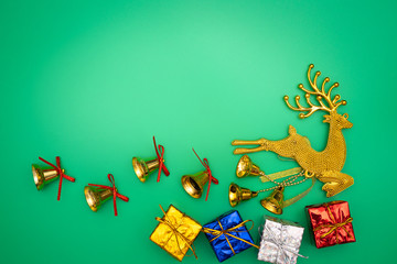 Christmas gloden reindeer composition. Christmas gift, gold reindeer and bell on green background. Flat lay, top view, copy space