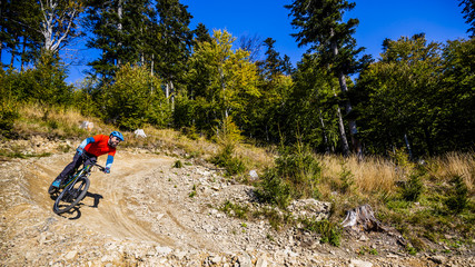 Mountain biker riding on bike in early spring mountains forest landscape. Man cycling MTB enduro flow trail track. Outdoor sport activity.