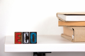 Eco - word from colored wooden letters un the whitte shelf near books