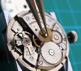 close up of watchmaker repairing watch mechanical caliber, taking small gear with  tweezers