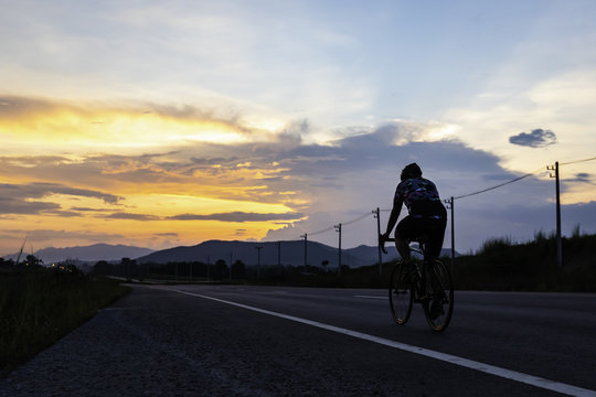 man riding bicycle on the highway at dusk