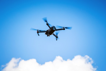 Quadrocopterfor shooting video in a blue sky with white clouds_