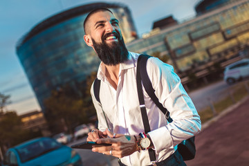 Portrait of a young caucasian businessman holding a digital tablet outdoor.