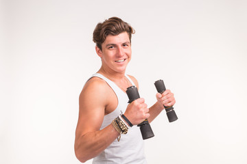 An attractive sporty man shows his biceps and smiling on white background