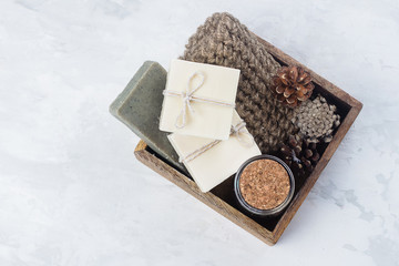 Spa, beauty skincare body concept. Handmade soap, coffee body scrub and body brush in wooden box on white marble background. Top view, copy space