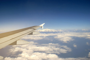 Fototapeta na wymiar Wing of an Airplane Flying above the Cloud with View of Mount Everest Background, Travelling Concept