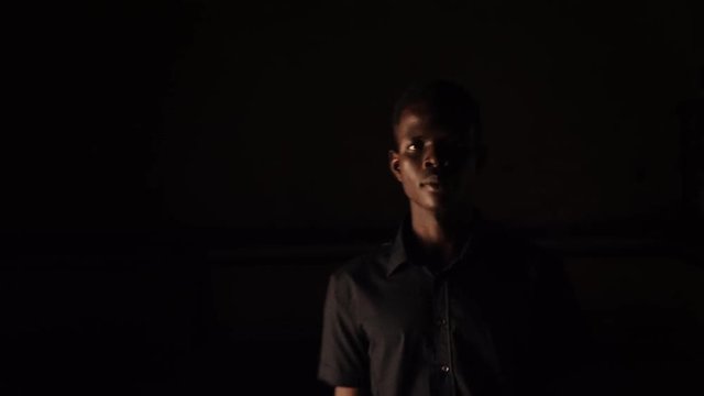 serious Young african man walking in the dark and staring at camera