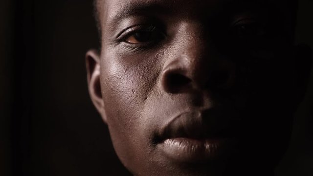 close up on young african man in the dark opening his eyes.Pride,gaze
