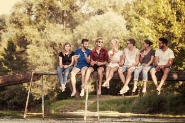 Fototapeta premium friends enjoying watermelon while sitting on the wooden bridge