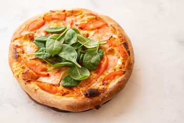 Traditional home made thin crust pizza with spinach, tomato, and mozzarella. Copy space.