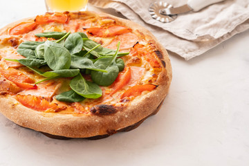 Traditional home made thin crust pizza with spinach, tomato, and mozzarella. Copy space.