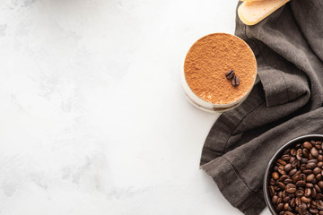 Traditional Italian dessert tiramisu in a glass on a white stone background. Copy space.