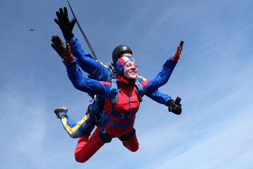 Fototapeta na wymiar Tandem skydiving. Happy girl and her instructor are n the sky.