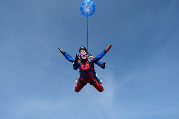 Naklejka na ściany i meble Tandem skydiving. Happy girl and her instructor are n the sky.
