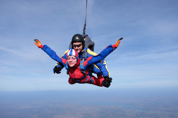 Tandem skydiving. Happy girl and her instructor are n the sky.