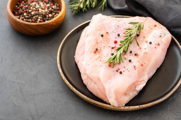 Turkey breast raw meat with spices on a dark background. Copy space.