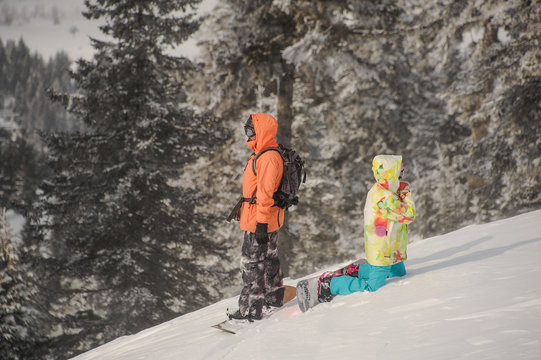Two snowboarders standing back to back on the hill in the mountain resort