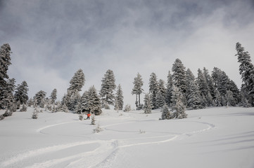 Man running down the mountain hill on the snowboard making trace