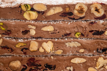 Traditional italian festive chocolate torrone or nougat with nuts close up. Copy space.