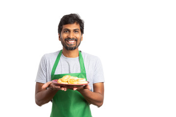 Indian man presenting donuts with happy expresion.