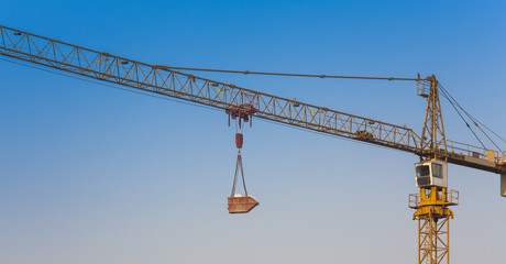 construction crane lifting cargo with clear blue sky background