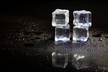 ice cubes reflection on black table background.