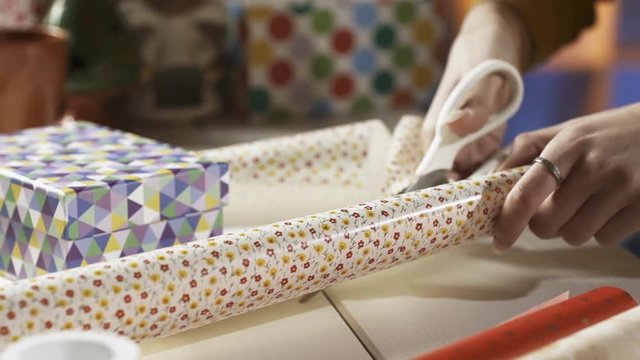 Woman cutting wrapping paper and preparing Christmas gifts