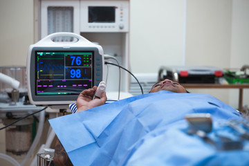 Hospital setting showing patient in operation with digital equipment monitoring health status...