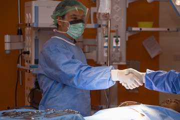 Two surgeons shaking hands under operating light, symbolizing teamwork, trust, and unity in medical...