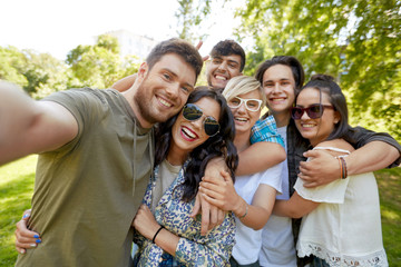 leisure, people and friendship concept - happy teenage friends taking selfie outdoors in summer