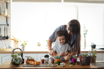 mother and son transplant plants at table
