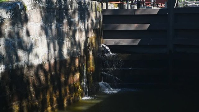 Water pouring out from the wall beside a closed sluice gate. Gota canal, Sweden.