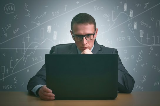 Stock trader is sitting by the table and is working on the laptop on the stock market. Technical analysis...