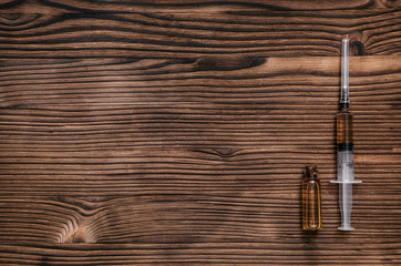 Syringe and ampoule with orange liquid medicine on the doctor table background with copy space.