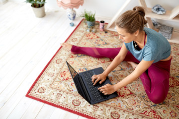 fitness, technology and healthy lifestyle concept - woman with laptop computer at yoga studio