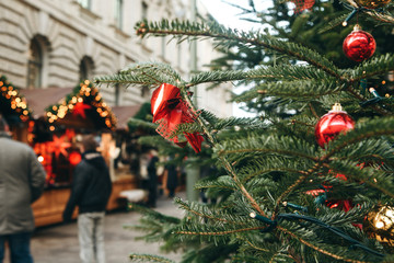 Christmas tree or fir branches in the foreground. The Christmas market in Germany is blurred in the...