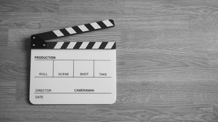 Obraz premium Clapper board or clap board or movie slate use in video production , film, cinema industry. It's white color on wood background.