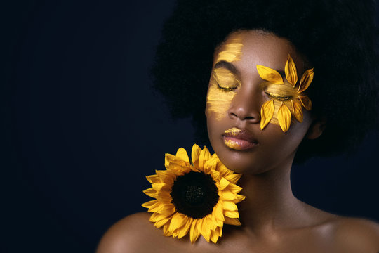 African woman with a sunflower and creative makeup on her face