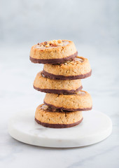 Homemade biscuit cookies with almond nuts and peanut butter on marble coasters on white kitchen table background.