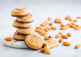 Homemade biscuit cookies with almond nuts and peanut butter on marble coasters on white kitchen table background.