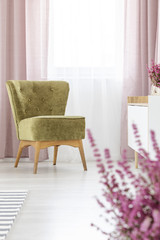 Vertical view of stylish olive green armchair in elegant living room with lilac curtains