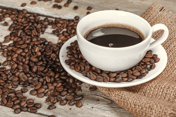 Cup of coffee with beans on table
